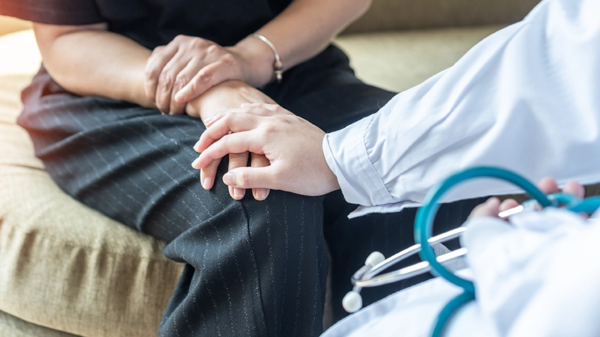 Doctor touching patient’s hand on knee.